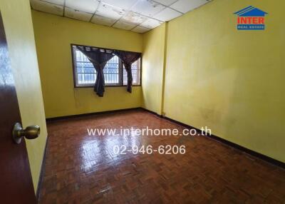 Empty bedroom with yellow walls and wooden flooring