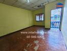 Empty room with tiled ceiling, wooden flooring, windows, and a small balcony