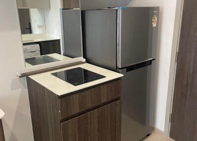 Modern kitchen area with stainless steel refrigerator and electric cooktop