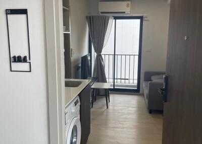 Interior view of an apartment showing living space with built-in kitchen and balcony