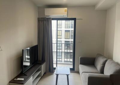 Modern living room with grey sofa, TV, and window with balcony view