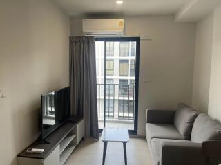 Modern living room with grey sofa, TV, and window with balcony view