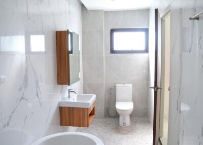 Modern bathroom with white marble walls, wall-mounted sink, and toilet