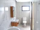 Modern bathroom with white marble walls, wall-mounted sink, and toilet