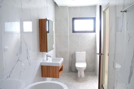 Modern bathroom with white marble walls, wall-mounted sink, and toilet