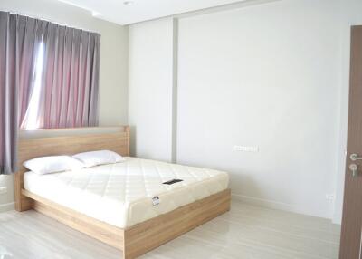 spacious bedroom with a large window and a wooden bed frame