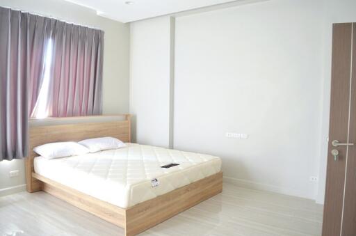 spacious bedroom with a large window and a wooden bed frame