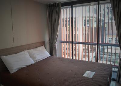 Bedroom with large window and brown bedspread