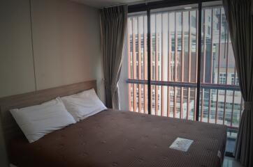 Bedroom with large window and brown bedspread