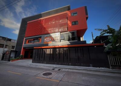 Modern multi-story red and black building exterior with commercial signage