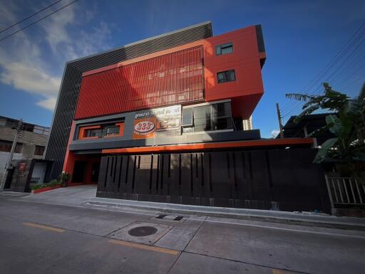 Modern multi-story red and black building exterior with commercial signage