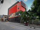 Modern multi-story commercial building with vibrant red accents