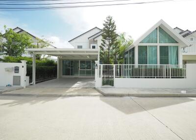 Modern front view of a house featuring a large window, driveway, and a well-maintained exterior