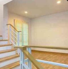 Staircase leading to a well-lit living space with wooden flooring