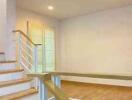 Staircase leading to a well-lit living space with wooden flooring