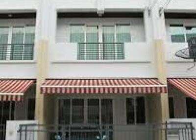 Three-story building facade with striped awning and gated parking area