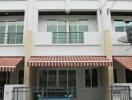 Three-story building facade with striped awning and gated parking area