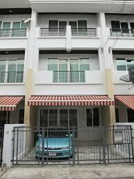 Three-story building facade with striped awning and gated parking area