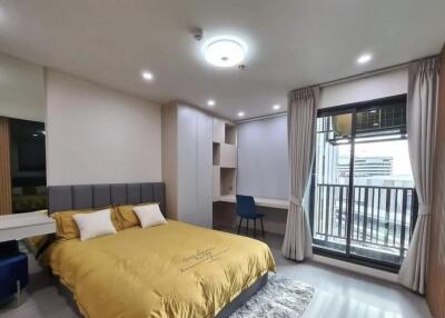 Modern bedroom with yellow bedding, built-in desk, and balcony.