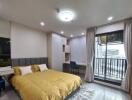 Modern bedroom with yellow bedding, built-in desk, and balcony.