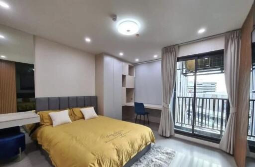 Modern bedroom with yellow bedding, built-in desk, and balcony.