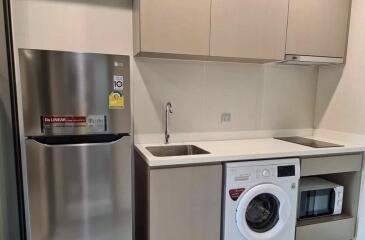 Modern kitchen with stainless steel appliances and laundry area