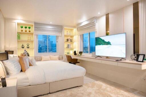 Well-lit bedroom with modern decor, large windows, built-in shelves, and a flat screen TV