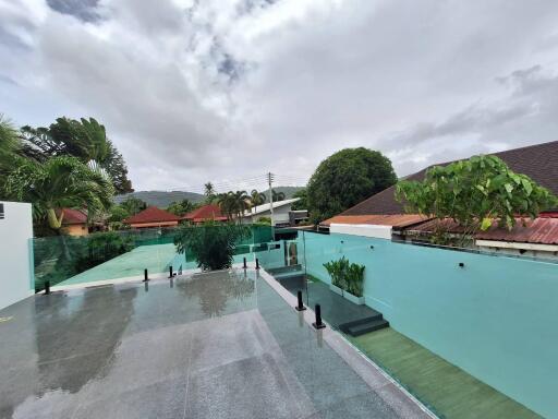 Outdoor area with a swimming pool and patio surrounded by greenery