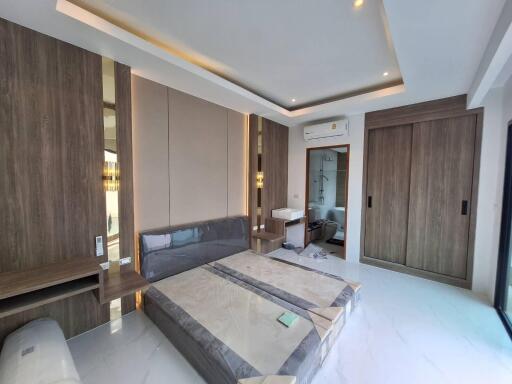 Modern bedroom with built-in wooden wardrobes, wall-mounted air conditioning, and contemporary furnishings