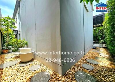 Pathway around the exterior of a building with greenery and potted plants