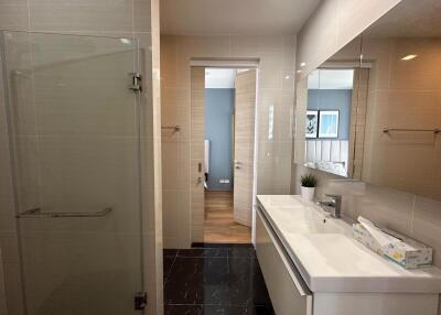 Modern bathroom with glass shower, large mirror, and dual sink vanity