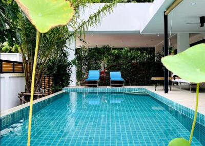 Modern outdoor pool area with surrounding greenery and lounge chairs