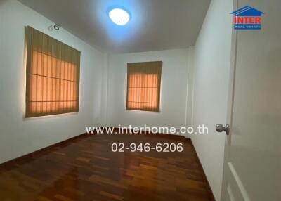 Spacious bedroom with wooden flooring and two windows