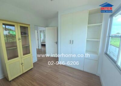 Bedroom with wooden flooring, white wardrobes, and large window