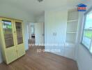 Bedroom with wooden flooring, white wardrobes, and large window