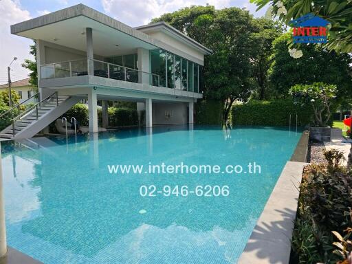 Swimming pool with adjacent modern building and lush greenery