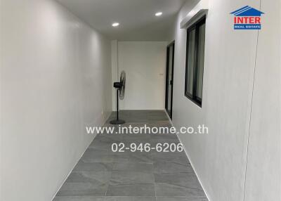 Narrow hallway with grey floor tiles and a stand fan