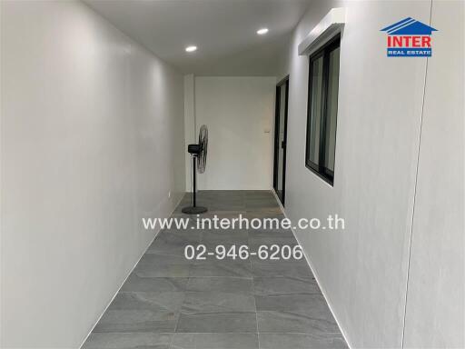 Narrow hallway with grey floor tiles and a stand fan