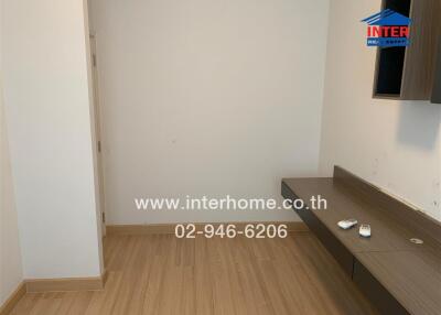 Empty bedroom with wooden floor and wall-mounted shelf