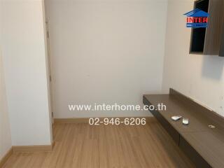 Empty bedroom with wooden floor and wall-mounted shelf