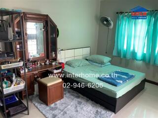 Bedroom with a double bed, dressing table, blue curtains, and an organized area