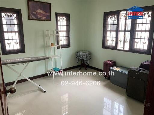 Bright bedroom with ironing board and luggage