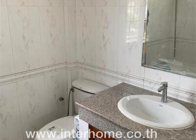 Bathroom with sink, toilet, and tiled walls