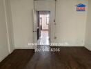 Empty bedroom with wooden floor and open door leading to another room