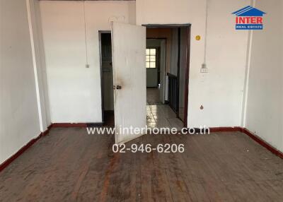 Empty bedroom with a wooden floor and adjacent hallway