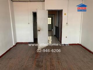 Empty bedroom with a wooden floor and adjacent hallway