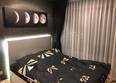 Modern bedroom with large bed, moon phase artwork and floor-to-ceiling window with curtains