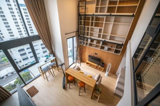 Modern living room with tall windows, open shelves, and a loft-style design