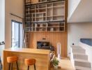 Modern living area with tall bookshelves, ladder, bar stools, and staircase