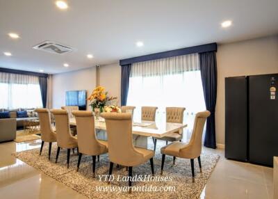 Modern dining room with large table, upholstered chairs, and decorative flowers